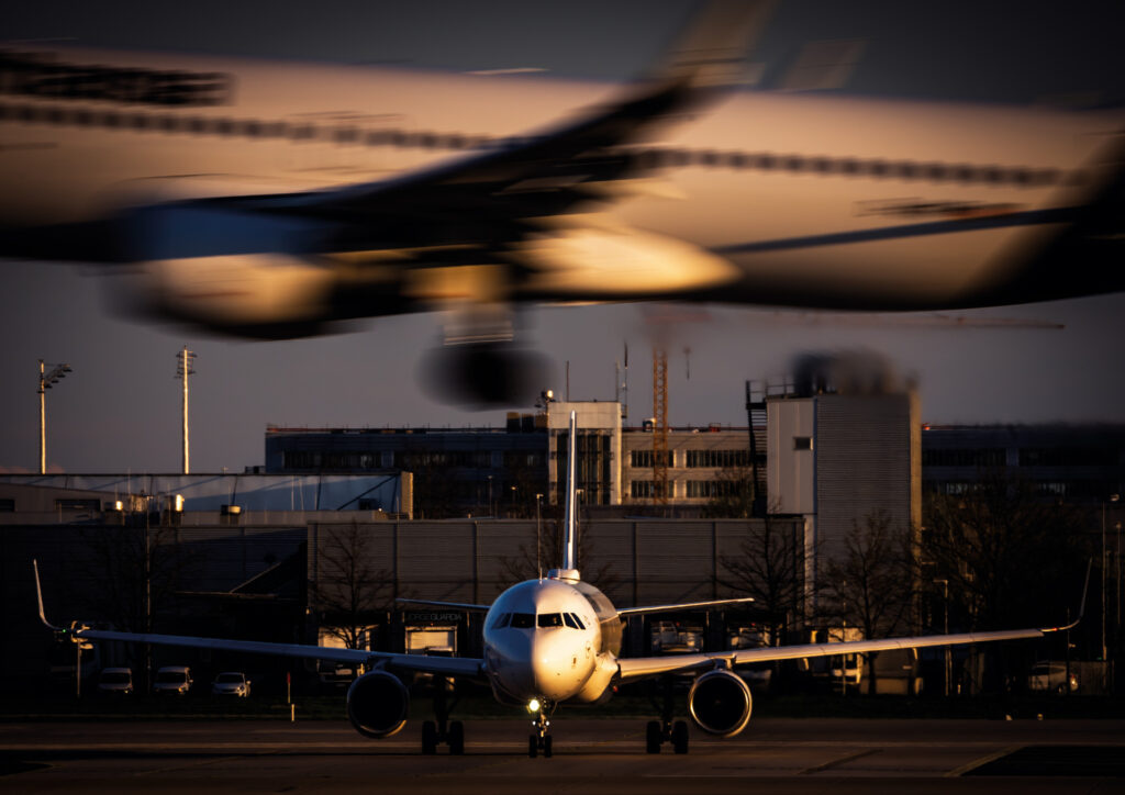 Lufthansa Airbus A320 waiting for takeoff at Munich Airport while another Lufthansa Airbus A320 is landing above it