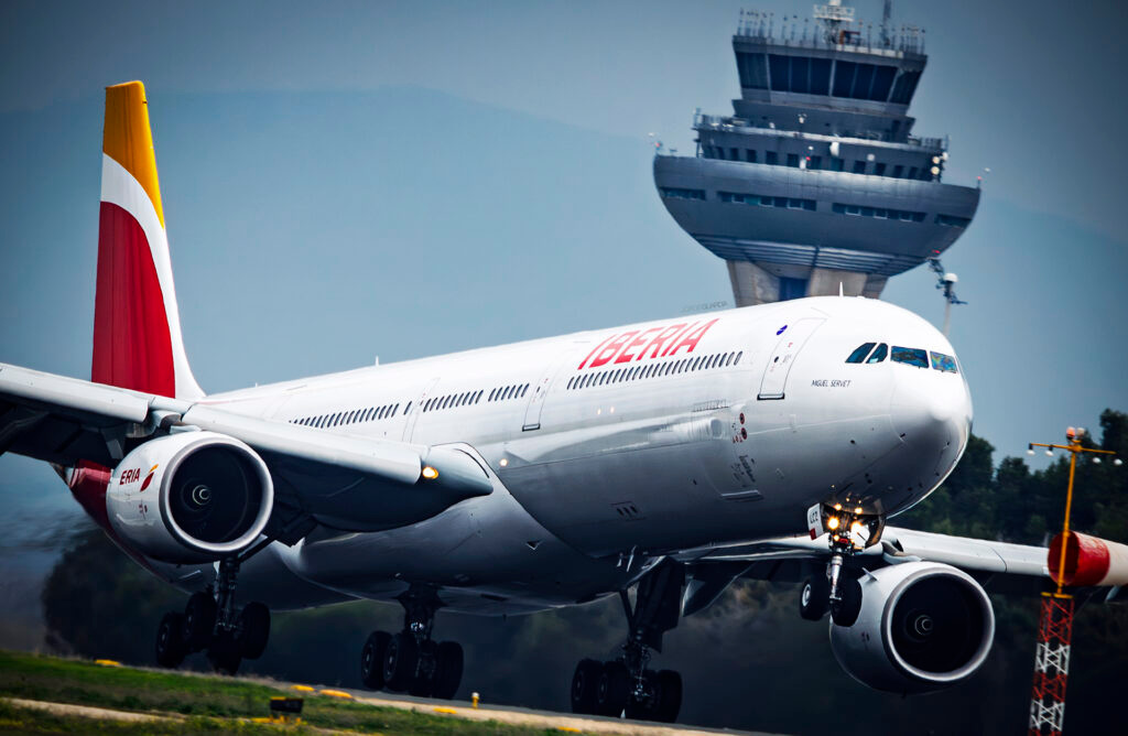 Iberia Airbus A340-600 taking off from Madrid Barajas with the T-4S control tower behind